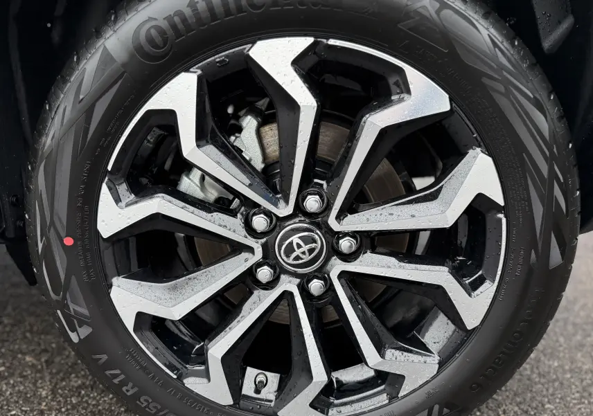 Gros plan sur la jante alliage noire et argentée de la Toyota Yaris Cross 130 CH DESIGN MY25 blanche, avec pneu Continental.