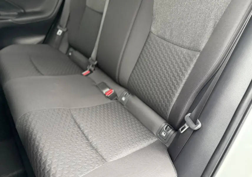 Vue rapprochée des sièges arrière gris foncé au tissu texturé d'une Toyota Yaris Cross blanche 2025.