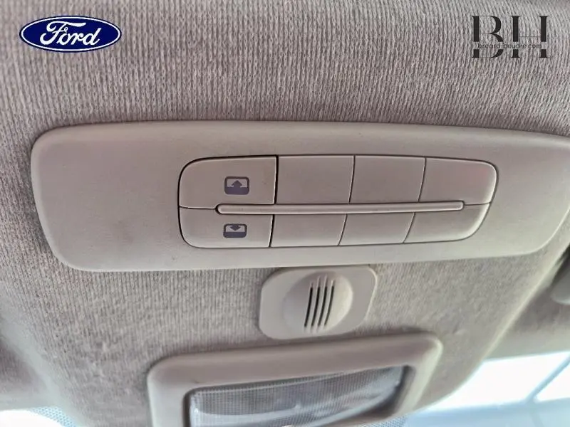 Boutons de commande du toit ouvrant électrique panoramique vus de l'intérieur du plafond, couleur beige clair.