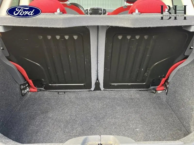 Coffre ouvert vu de l'arrière d'une Fiat 500 noire, montrant la banquette arrière et l'intérieur rouge.