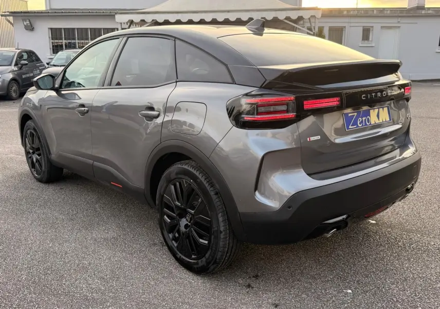 Vue 3/4 arrière droite d'une Citroën C4 hybride gris Mercury avec jantes noires et feux arrière LED distinctifs.