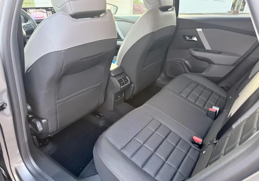 Vue intérieure arrière droite du Citroën C4 hybride gris Mercury, montrant les sièges arrière et les dossiers avant bicolores.