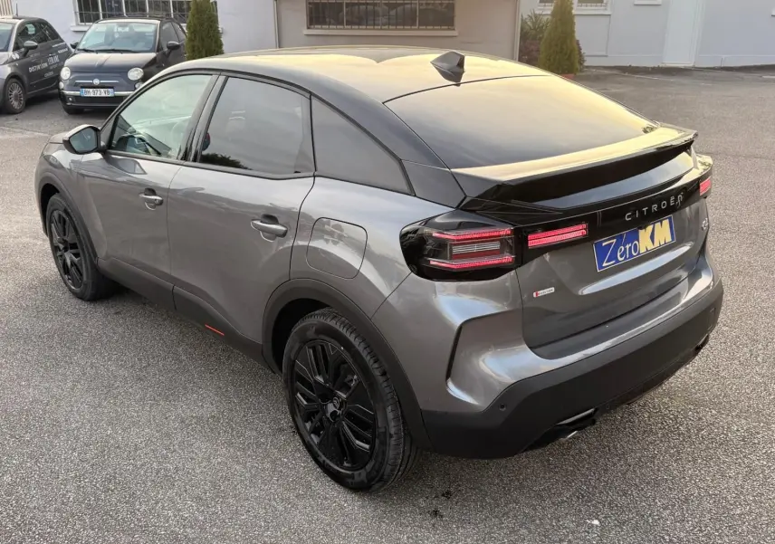 Vue 3/4 arrière droite d'une Citroën C4 hybride gris Mercury avec jantes noires et feux arrière LED distinctifs.