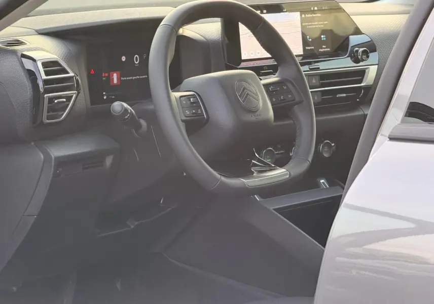 Vue intérieure côté conducteur de la Citroën C4 hybride gris Mercury, avec tableau de bord numérique et écran tactile central.