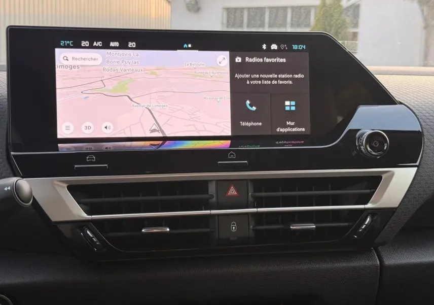 Vue rapprochée du tableau de bord du Citroën C4 hybride 2025 avec écran tactile et commandes de climatisation.