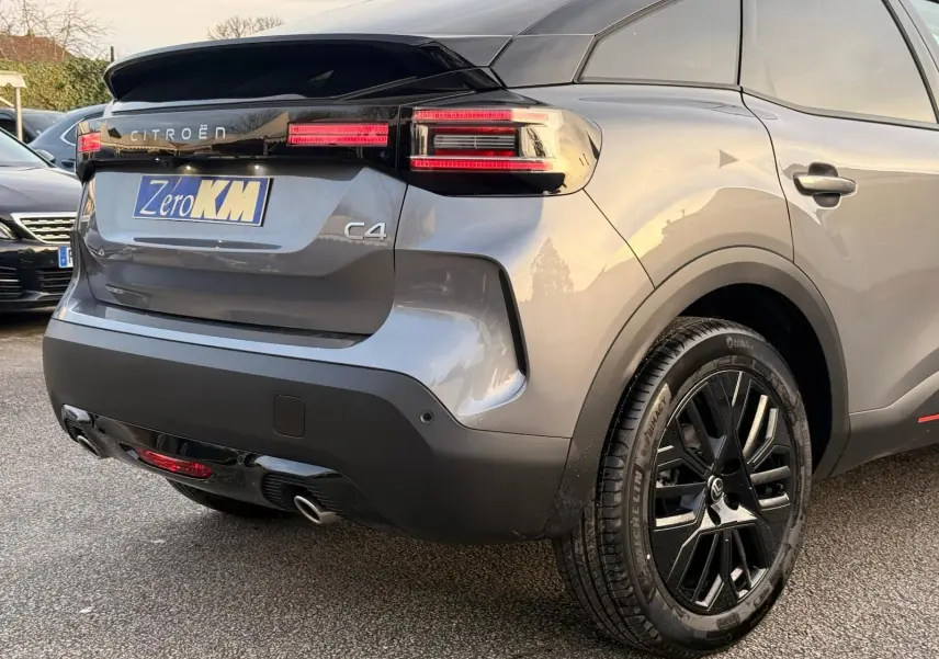 Vue 3/4 arrière droite d'une Citroën C4 gris Mercury 2025 avec feux LED et jantes noires distinctives.