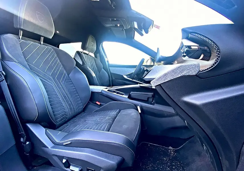 Vue intérieure côté passager avant du Peugeot 5008 Hybrid 145 GT e-dcs6 2025, sièges noirs avec surpiqûres et tableau de bord moderne.