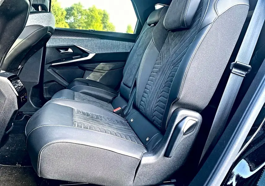 Vue latérale des sièges arrière noirs en tissu et cuir du Peugeot 5008 Hybrid 145 GT 2025 avec appuie-tête et ceinture.