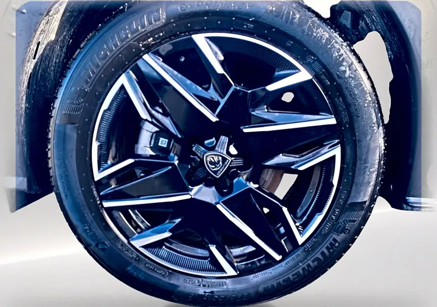 Gros plan sur la jante alu noire et argentée du Peugeot 5008 Hybrid 145 GT e-dcs6, pneu Michelin visible.