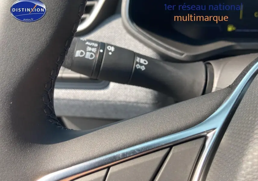 Gros plan sur les commandes au volant d'une Renault Clio V noire, mettant en valeur la finition techno et les détails du tableau de bord.