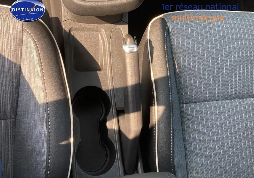 Vue plongeante sur l'accoudoir central et les sièges en tissu gris de la Renault Clio V 1.6 e-tech 145 techno.