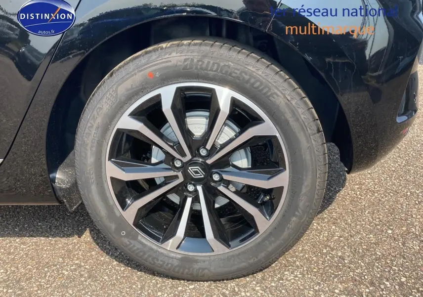 Gros plan sur la jante alu noire et argentée côté gauche d'une Renault Clio V noir étoile.