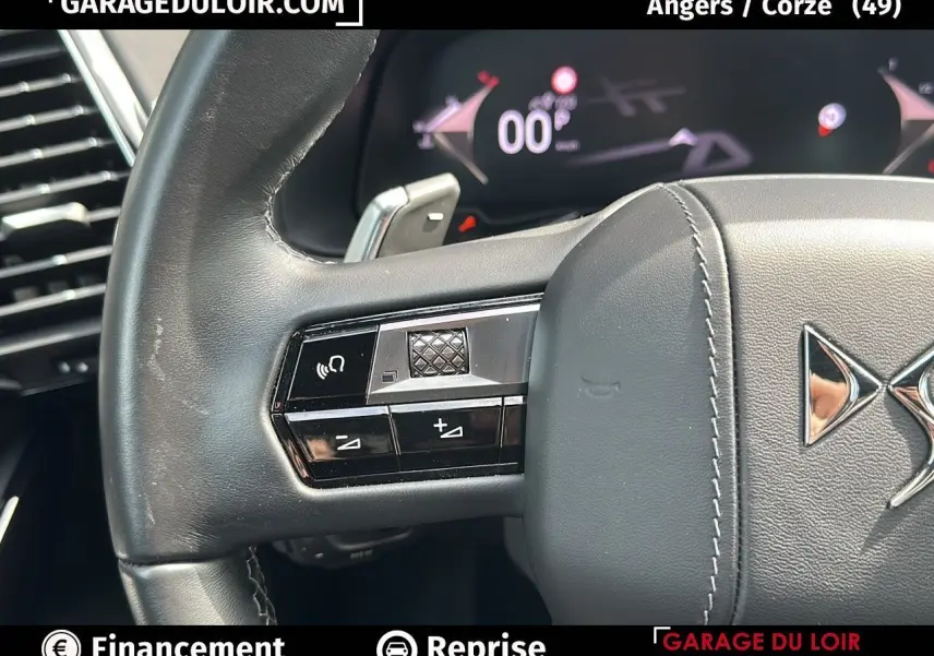 Gros plan sur le volant en cuir noir du DS7 7 BlueHDi 130 EAT8 Rivoli avec commandes intégrées et tableau de bord numérique.