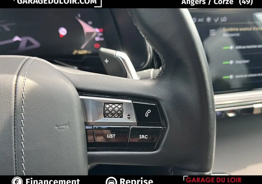 Gros plan sur les commandes au volant en cuir noir du DS7 7 BlueHDi 130 EAT8 Rivoli, avec écran numérique en arrière-plan.