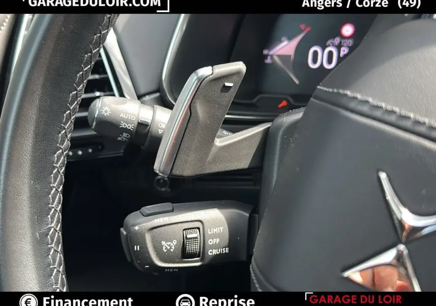 Gros plan sur les commandes au volant en cuir noir du DS7 7 BlueHDi 130 EAT8 Rivoli, affichage numérique en arrière-plan.