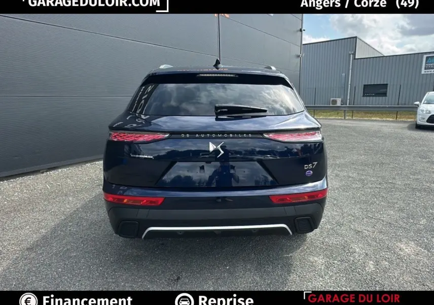 Vue arrière d'un DS7 bleu saphir avec feux 3D et logo DS Automobiles sur un parking extérieur.