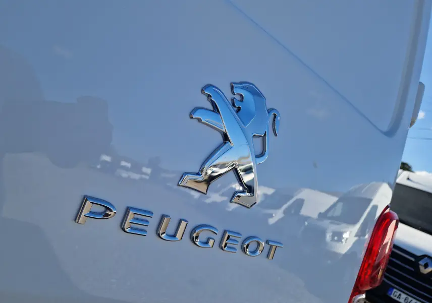 Gros plan sur l'arrière blanc d'un Peugeot Expert Fourgon avec le logo lion chromé et le nom PEUGEOT visible.
