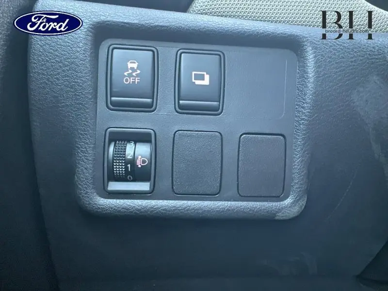 Gros plan sur les commandes de réglage des phares et de l'ESP côté gauche du tableau de bord d'une Nissan Micra gris acier 2018.