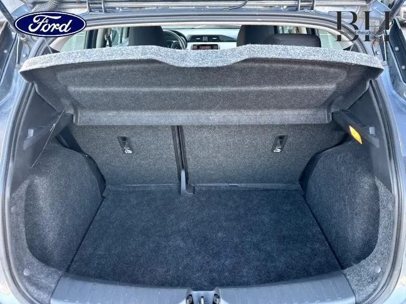 Coffre ouvert vu de l'arrière d'une Nissan Micra gris acier 2018, montrant l'espace de chargement vide et la tablette cache-bagages.