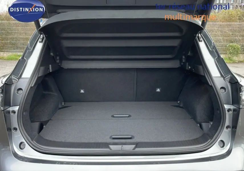 Coffre ouvert vu de l'arrière du Nissan Qashqai 1.5 E-POWER gris squale métal, montrant un espace de chargement plat et spacieux.