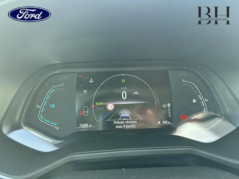 Tableau de bord numérique de Renault Clio hybride gris Titanium, affichant 0 km/h et message de révision à prévoir.