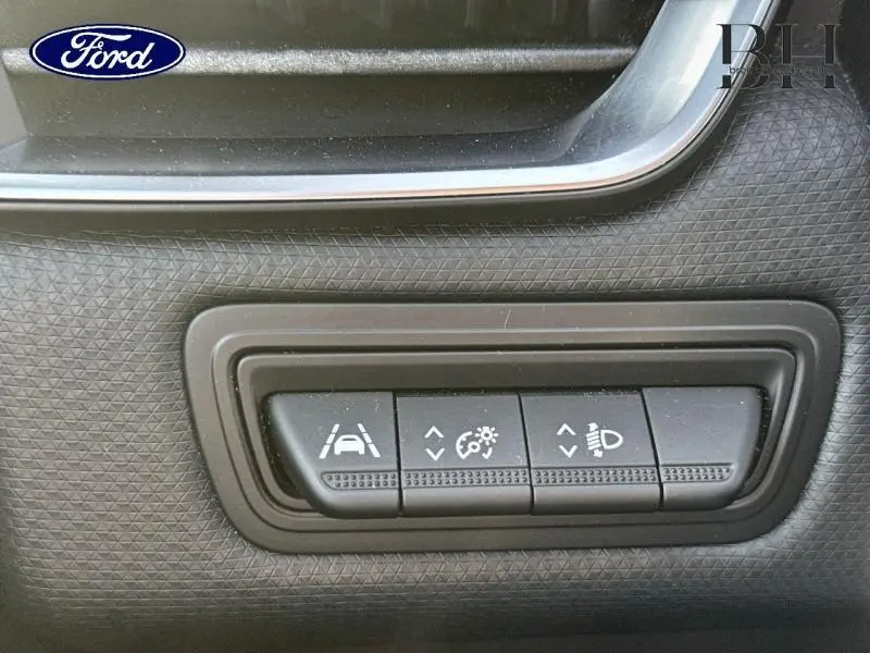 Gros plan sur les commandes d'assistance et réglage des phares dans l'habitacle de la Renault Clio gris titanium.