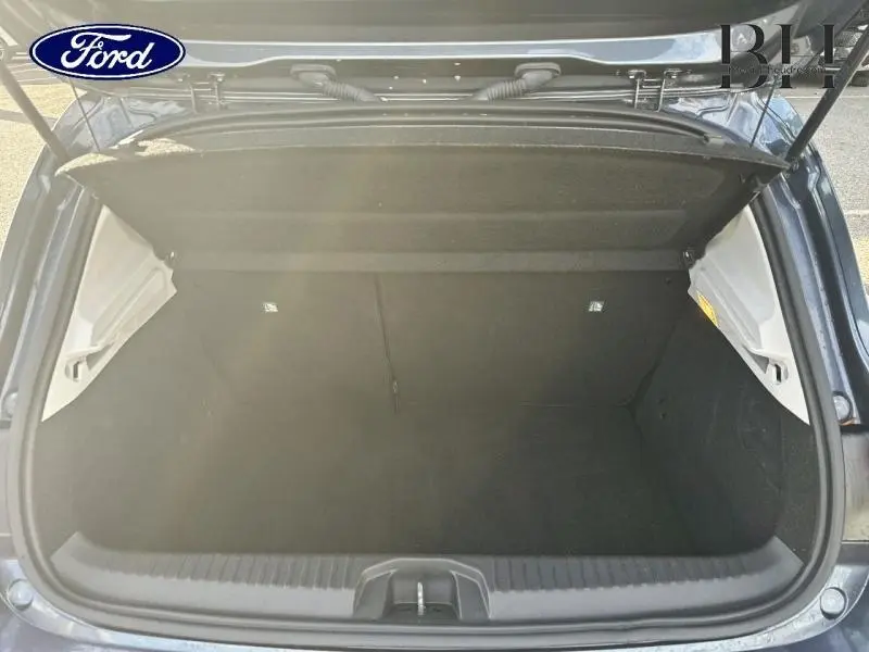 Coffre ouvert vu de l'arrière d'une Renault Clio gris Titanium, montrant un espace de rangement vide et propre.