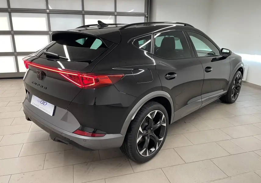 Vue 3/4 arrière droite du CUPRA Formentor 1.5 TSI 150 DSG7 VZ-LINE 2023 en noir minuit métallisé, avec feux arrière LED allumés.