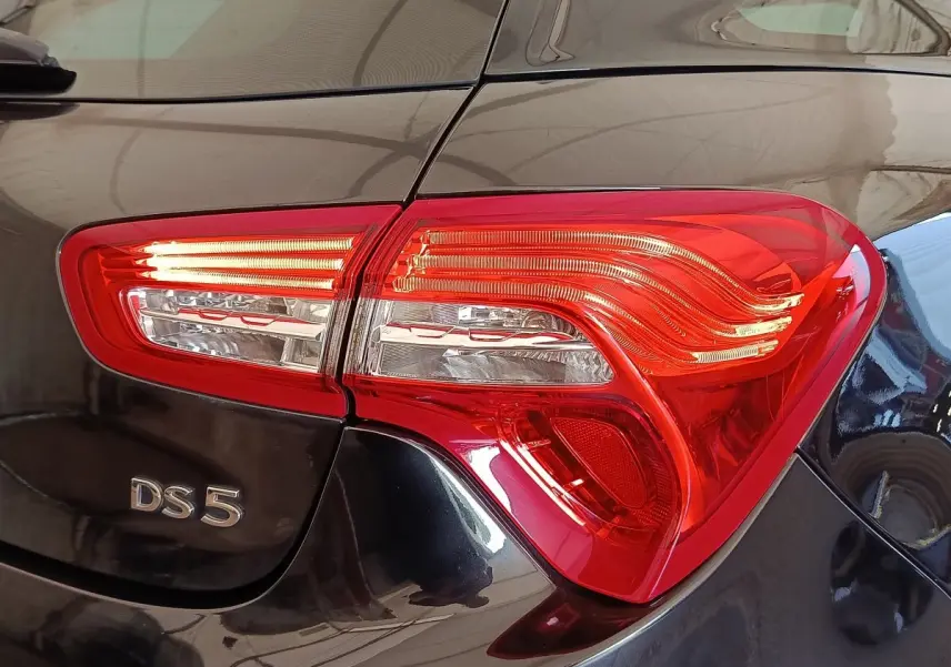 Gros plan sur le feu arrière droit rouge et le logo DS5 d’une DS5 noire brillante, vue arrière côté droit.