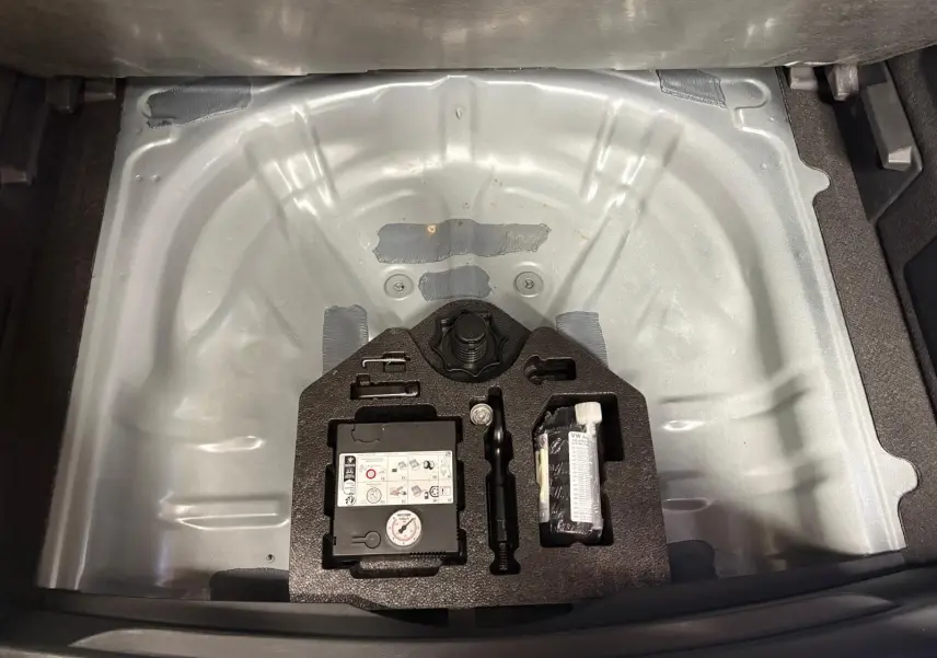 Coffre ouvert du CUPRA Formentor gris magnétique 2023 montrant la roue de secours et le kit de réparation.