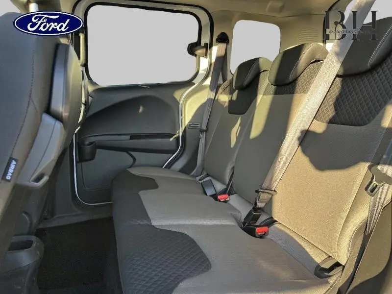 Vue intérieure de la banquette arrière grise du Ford Tourneo Courier 2022, avec ceintures de sécurité et vitres teintées.