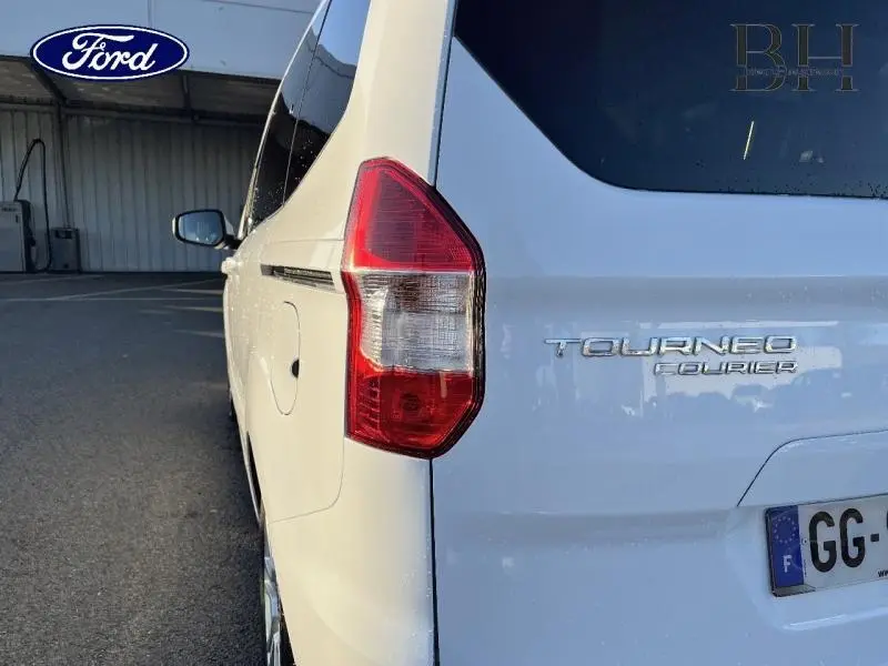 Vue arrière côté gauche du Ford Tourneo Courier blanc Glacier avec feu arrière et logo visible.