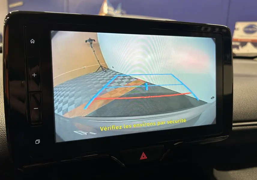 Écran intérieur montrant la caméra de recul avec lignes de guidage, tableau de bord noir d’une Toyota Yaris Cross gris minéral.
