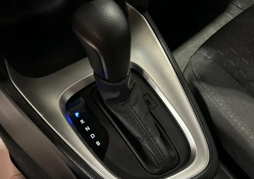 Gros plan sur le levier de vitesses automatique noir et argenté de la Toyota Yaris Cross, avec siège tissu gris visible à droite.