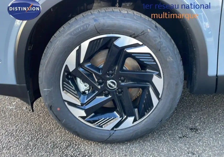 Gros plan sur la roue avant gauche du Nissan Qashqai gris argile métal, mettant en valeur la jante noire et argentée au design moderne.