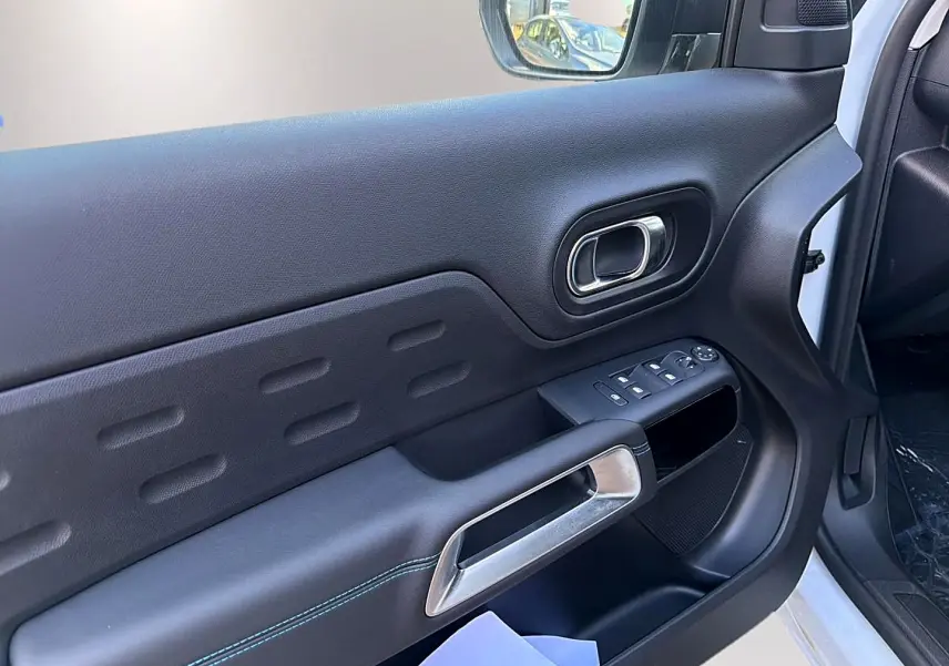 Vue intérieure côté conducteur de la porte noire avec poignée argentée et commandes des vitres du Citroën C5 Aircross blanc.