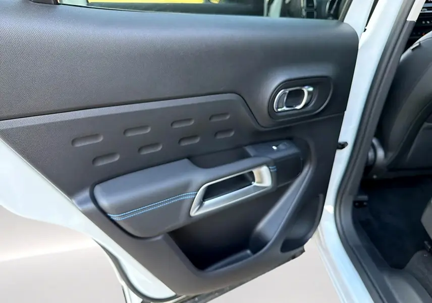 Vue rapprochée de la porte arrière gauche noire avec surpiqûres bleues sur un Citroën C5 Aircross blanc 2025.