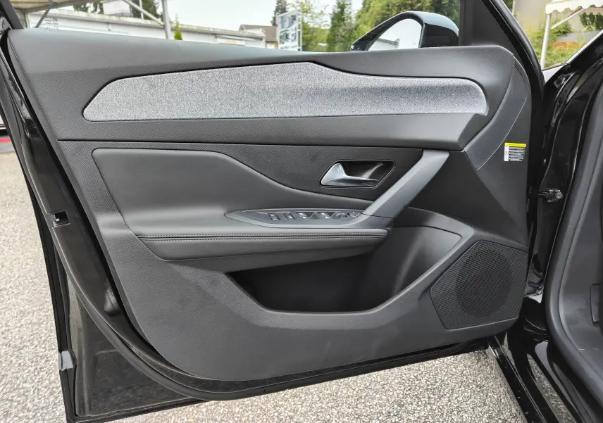 Vue rapprochée de la porte avant gauche noire d'une Peugeot 308 PureTech 130 Allure Pack avec garniture tissu grise.