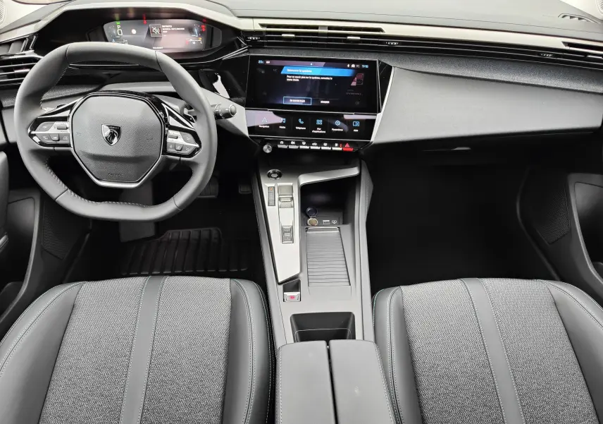 Vue intérieure de face du poste de conduite de la Peugeot 308 PureTech 130 Allure Pack 2023, avec tableau de bord numérique et écran tactile central.