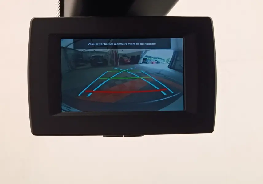 Écran intérieur affichant la caméra de recul du Peugeot Partner blanc, avec lignes de guidage colorées.