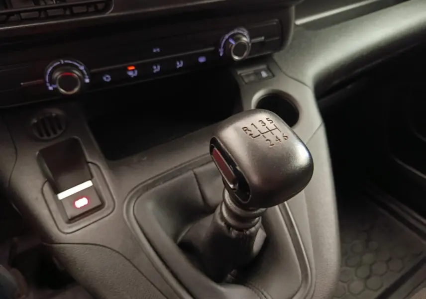 Gros plan sur le levier de vitesses manuel noir du Peugeot Partner 2022 avec console centrale et commandes de climatisation.