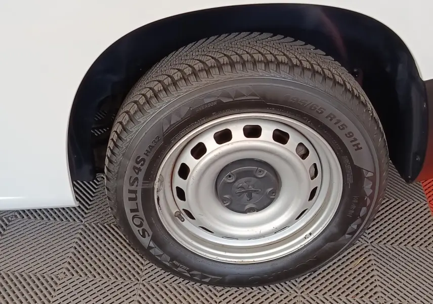 Gros plan sur la roue arrière droite en jante acier argentée du Peugeot Partner blanc de 2022.