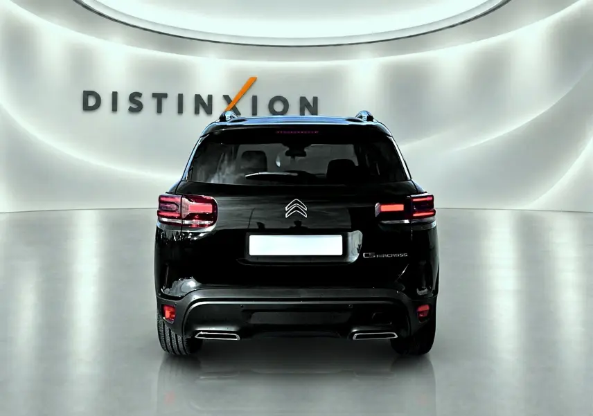 Vue arrière d'un Citroën C5 Aircross noir 2025 dans un showroom avec éclairage moderne et logo Distinxion en arrière-plan.