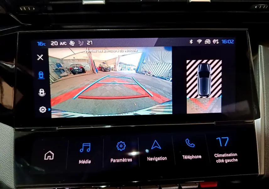Écran tactile central de la Peugeot 308 PHEV 180 GT montrant la caméra de recul et l'aide au stationnement arrière.