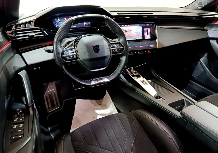 Intérieur de la Peugeot 308 PHEV 180 GT 2022, vue du poste de conduite avec volant compact et écran tactile central.