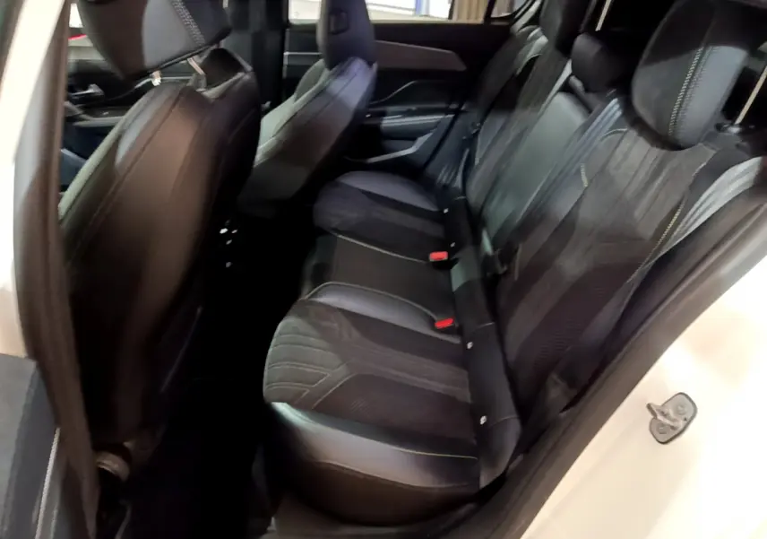 Vue côté droit de l'habitacle arrière d'une Peugeot 308 PHEV 180 E-EAT8 GT blanche avec sièges noirs en cuir et tissu.