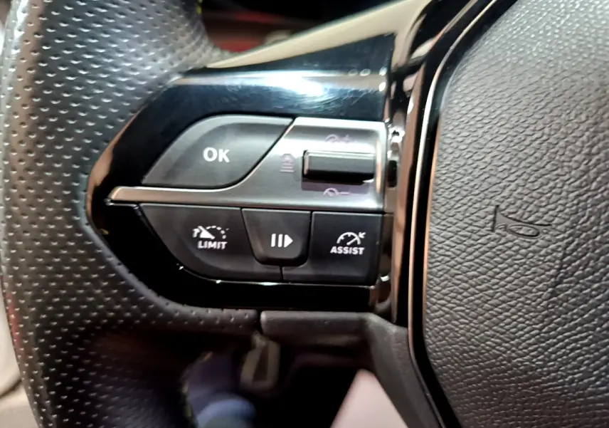 Gros plan sur les commandes gauche du volant en cuir perforé de la Peugeot 308 PHEV 180 E-EAT8 GT 2022.