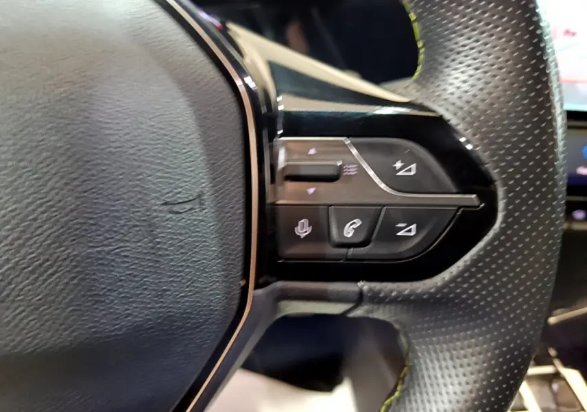 Gros plan sur les commandes du volant en cuir perforé de la Peugeot 308 PHEV 180 E-EAT8 GT blanche, côté droit.