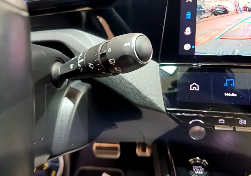 Gros plan sur la commande d’essuie-glace et l’écran tactile du tableau de bord de la Peugeot 308 PHEV blanche de 2022.