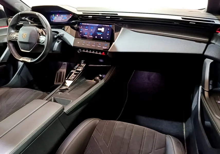 Intérieur Peugeot 308 PHEV 180 GT 2022 vu côté conducteur, tableau de bord moderne avec écran tactile et volant cuir.